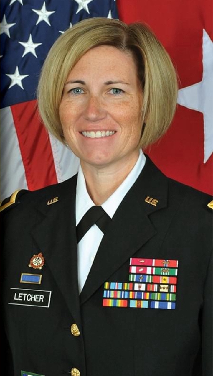 Michelle Letcher smiles in uniform in front of an American flag.