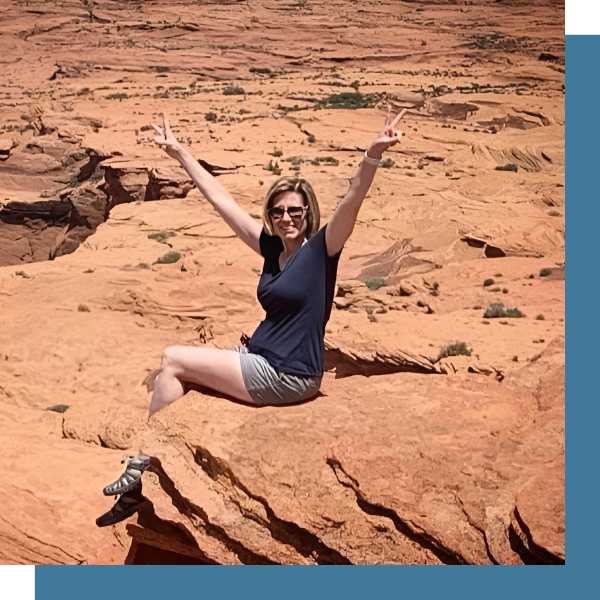 Michelle Letcher sits on a rock with her hands in peace signs.