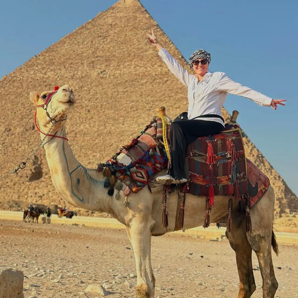 Michelle poses on the back of a camel in front of the pyramids.