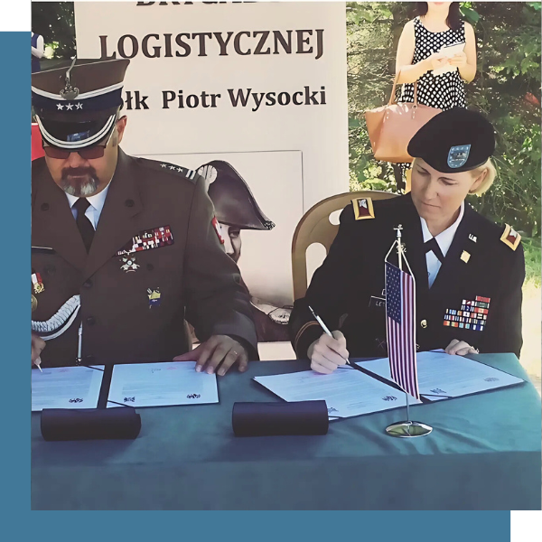 Michelle signs a document beside a Polish ambassador
